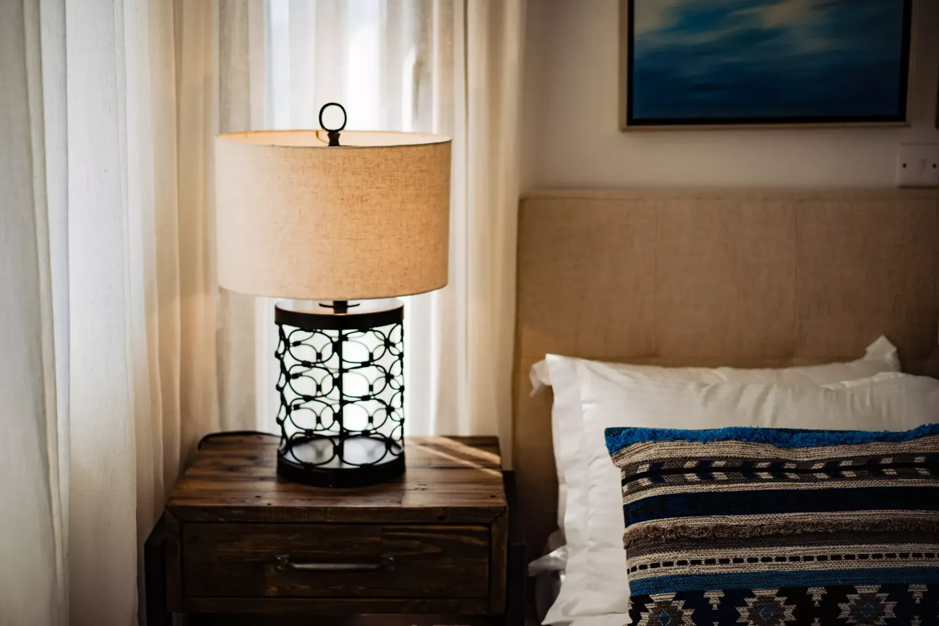 A lamp is sitting on a nightstand next to a bed.