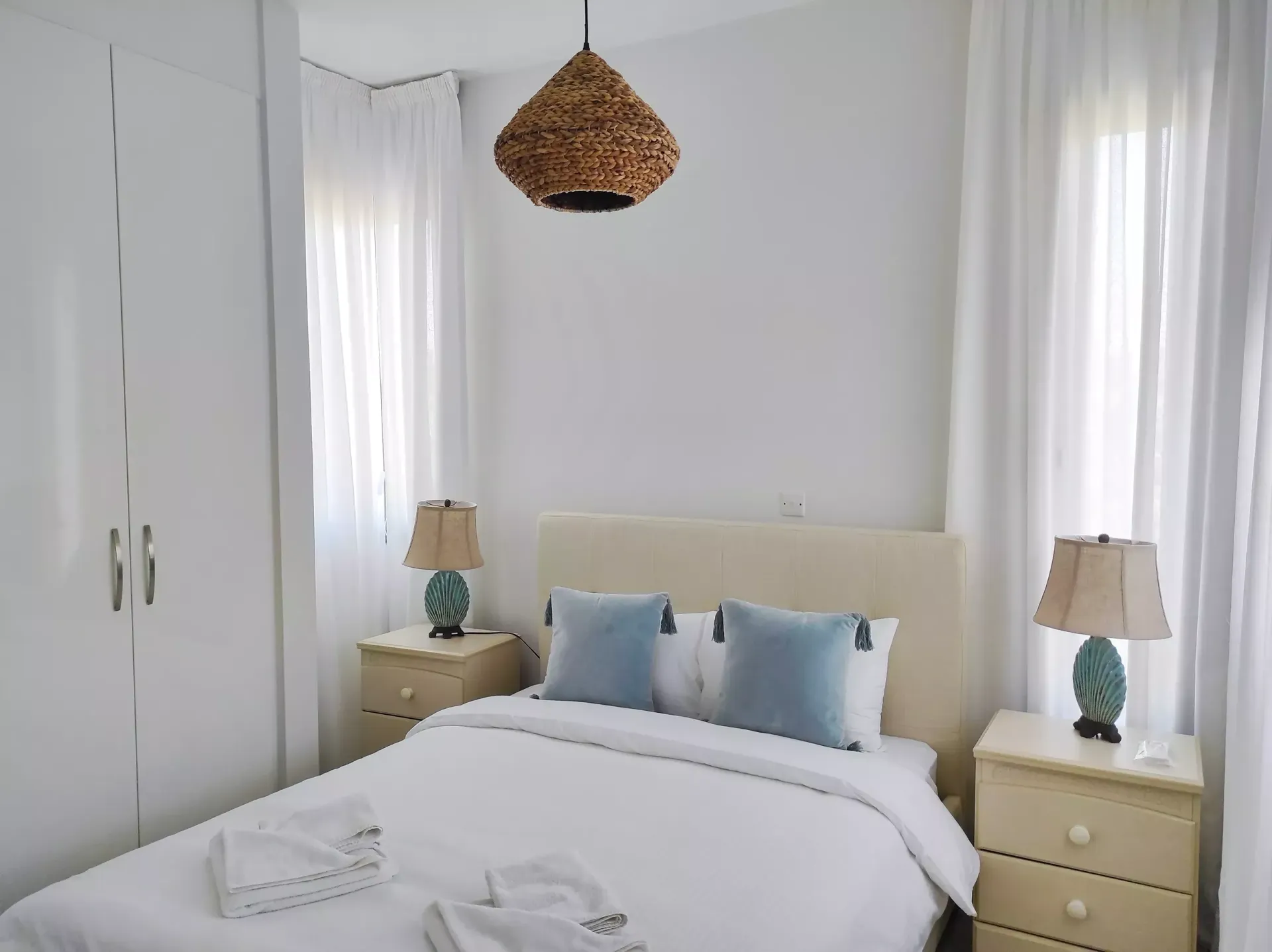 A bedroom with a bed , two nightstands , two lamps and a window.