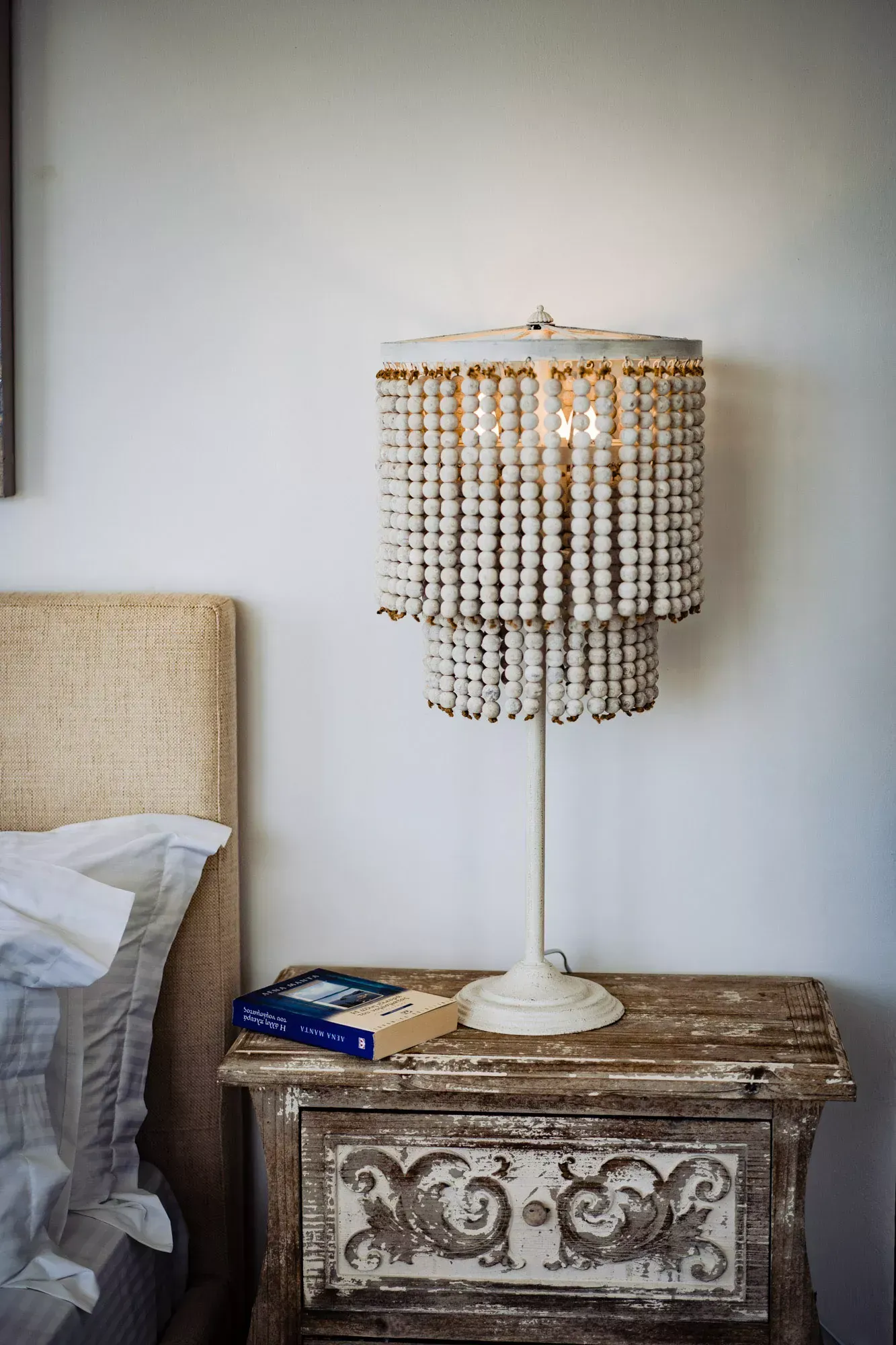 A lamp is sitting on a nightstand next to a bed.