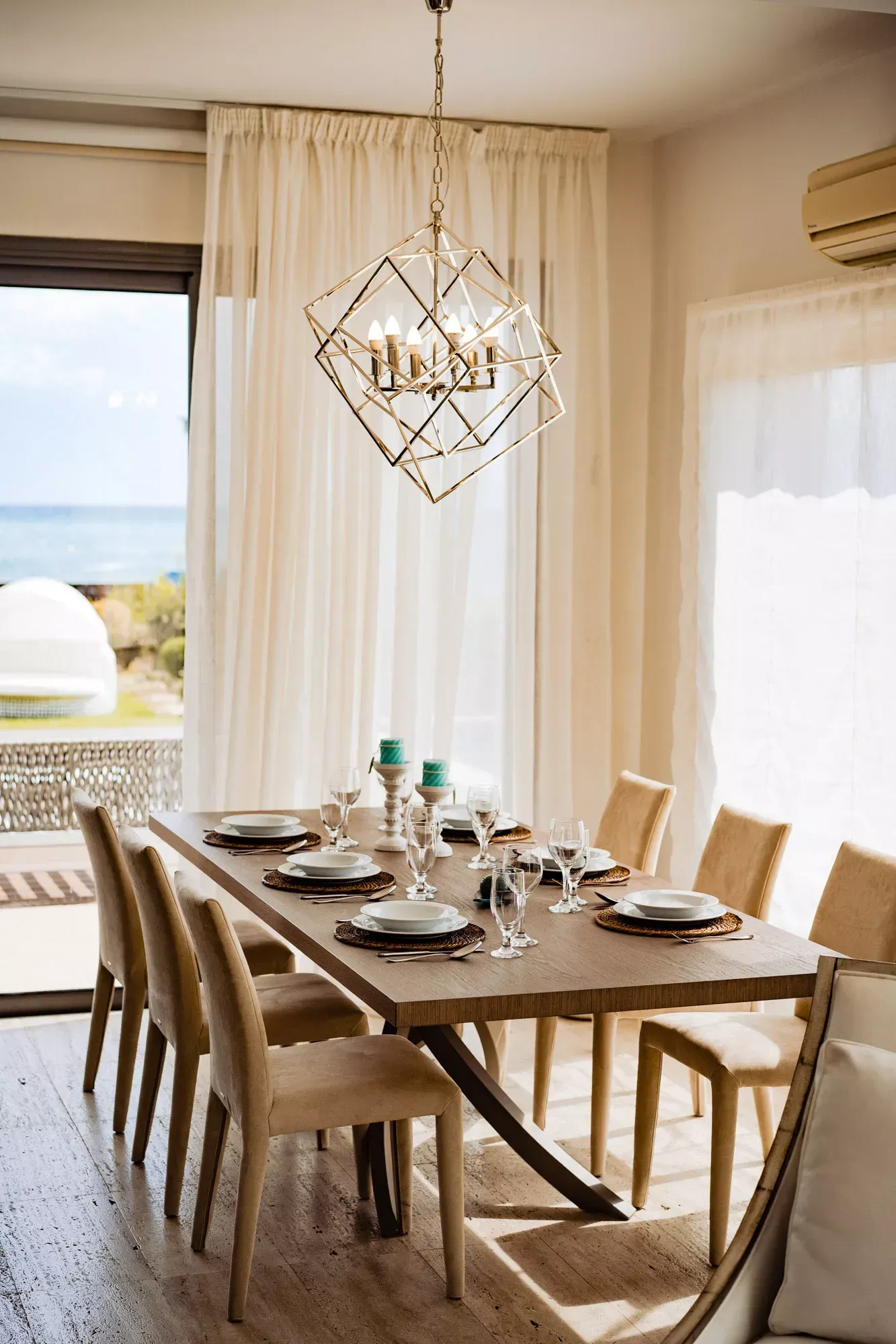 A dining room with a long table and chairs and a chandelier.