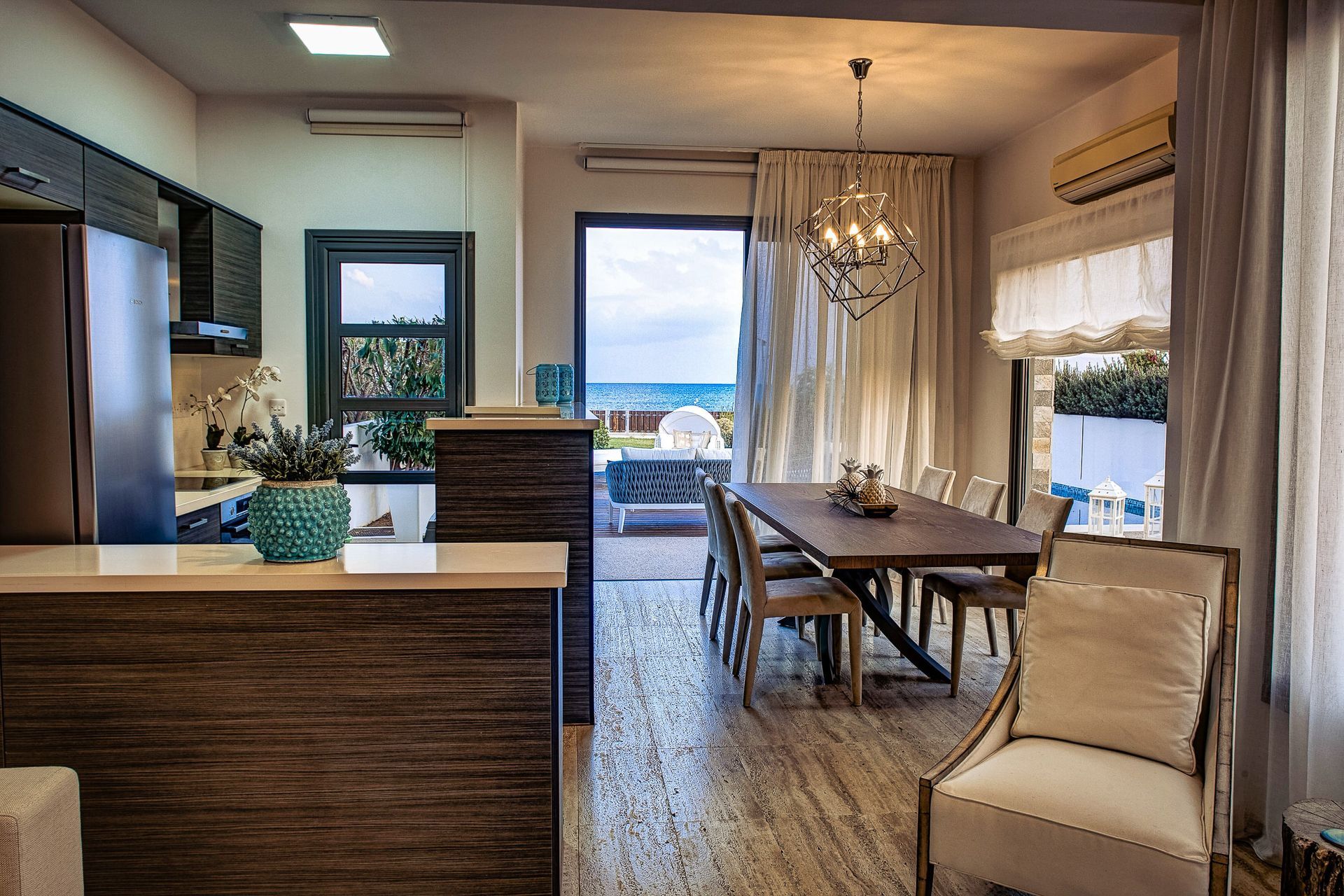 A living room with a table and chairs and a view of the ocean.