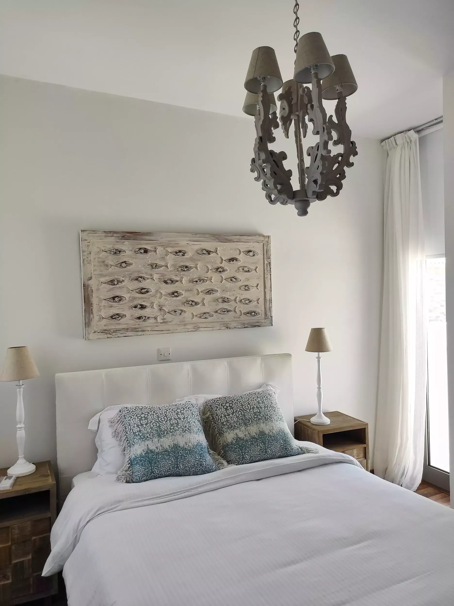 A bedroom with a bed , nightstands , lamps and a chandelier.