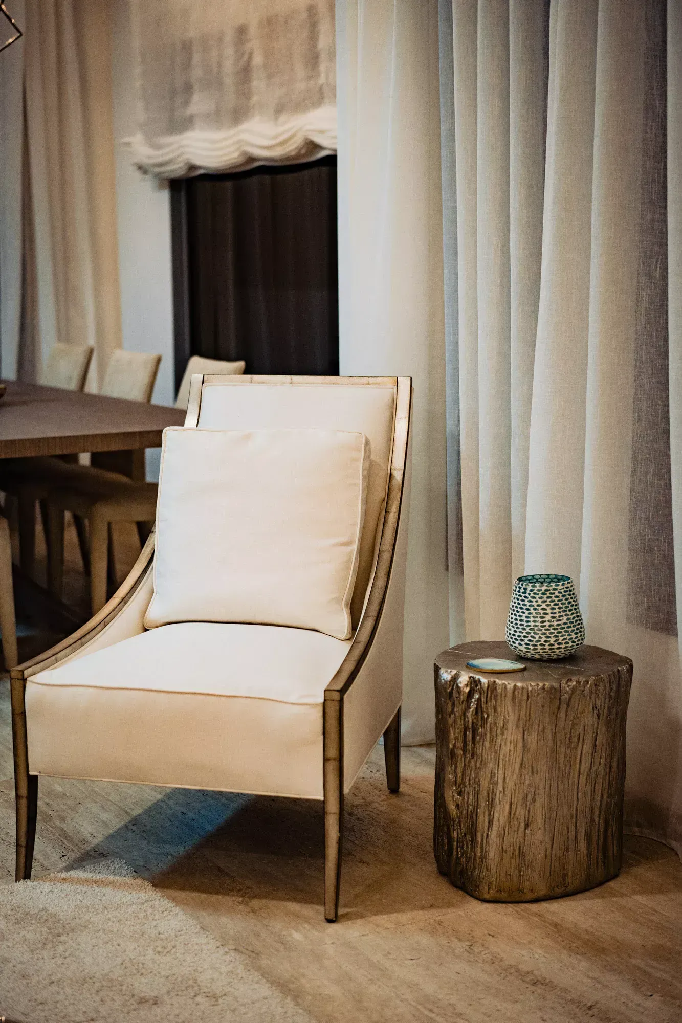 A chair is sitting next to a wooden stump in a living room.