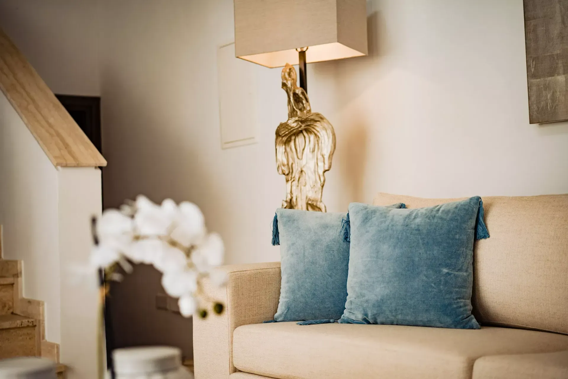 A living room with a couch , lamp , and blue pillows.