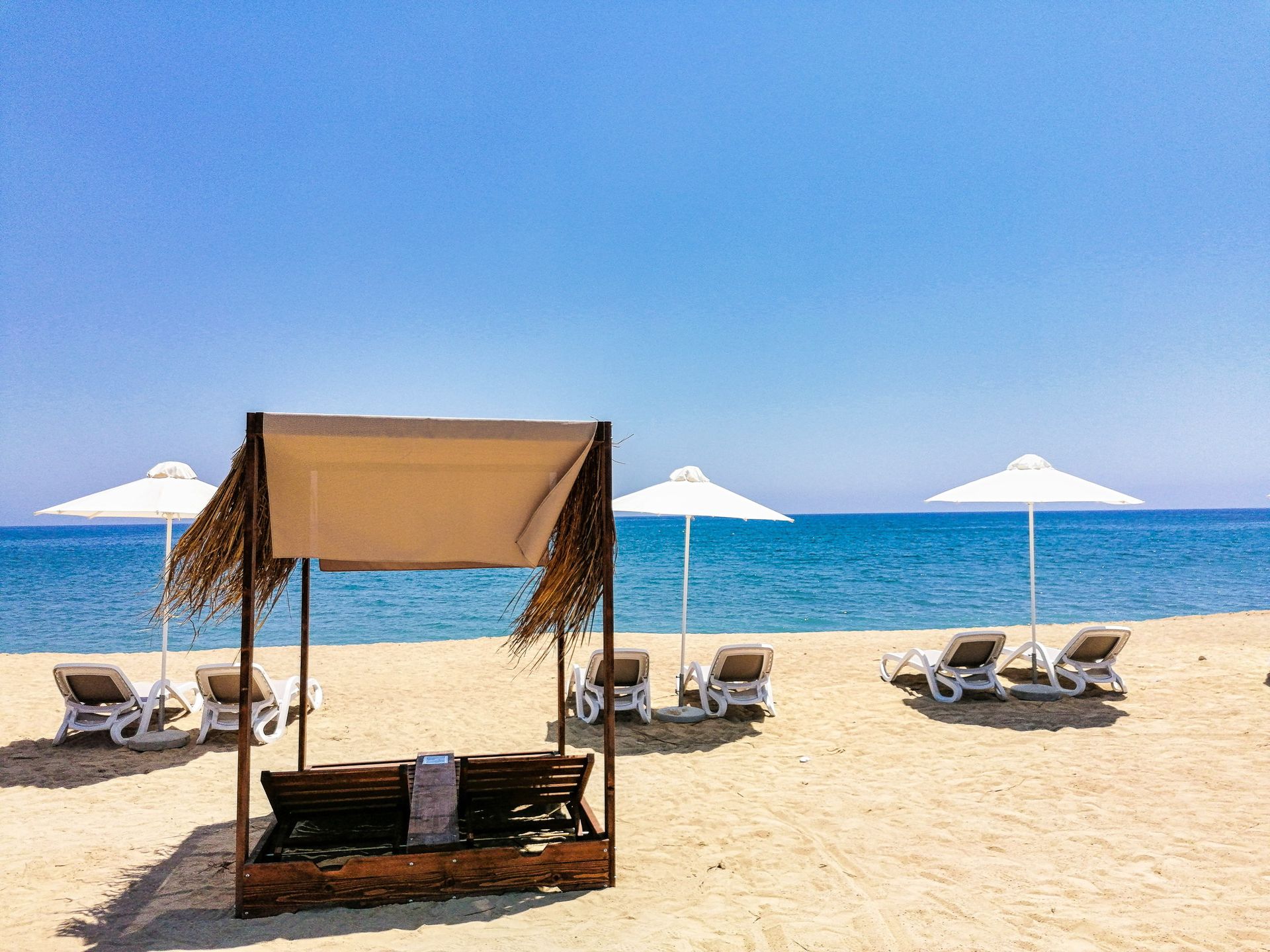 A beach with a canopy , chairs and umbrellas.