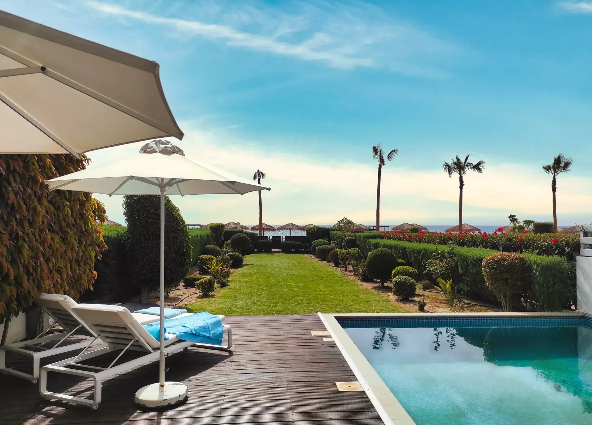 A swimming pool with umbrellas and lounge chairs next to it