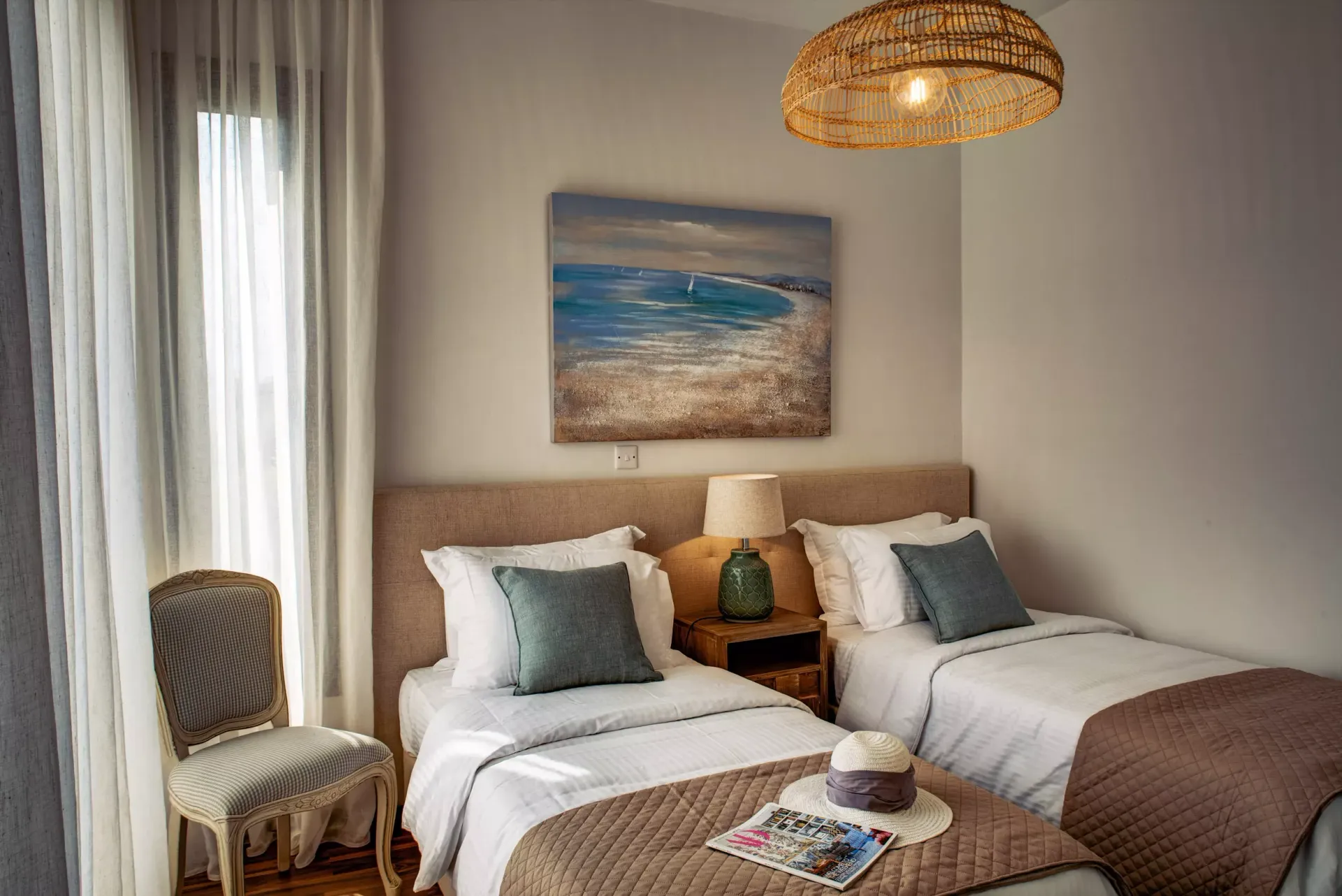 A bedroom with two beds , a chair and a painting on the wall.