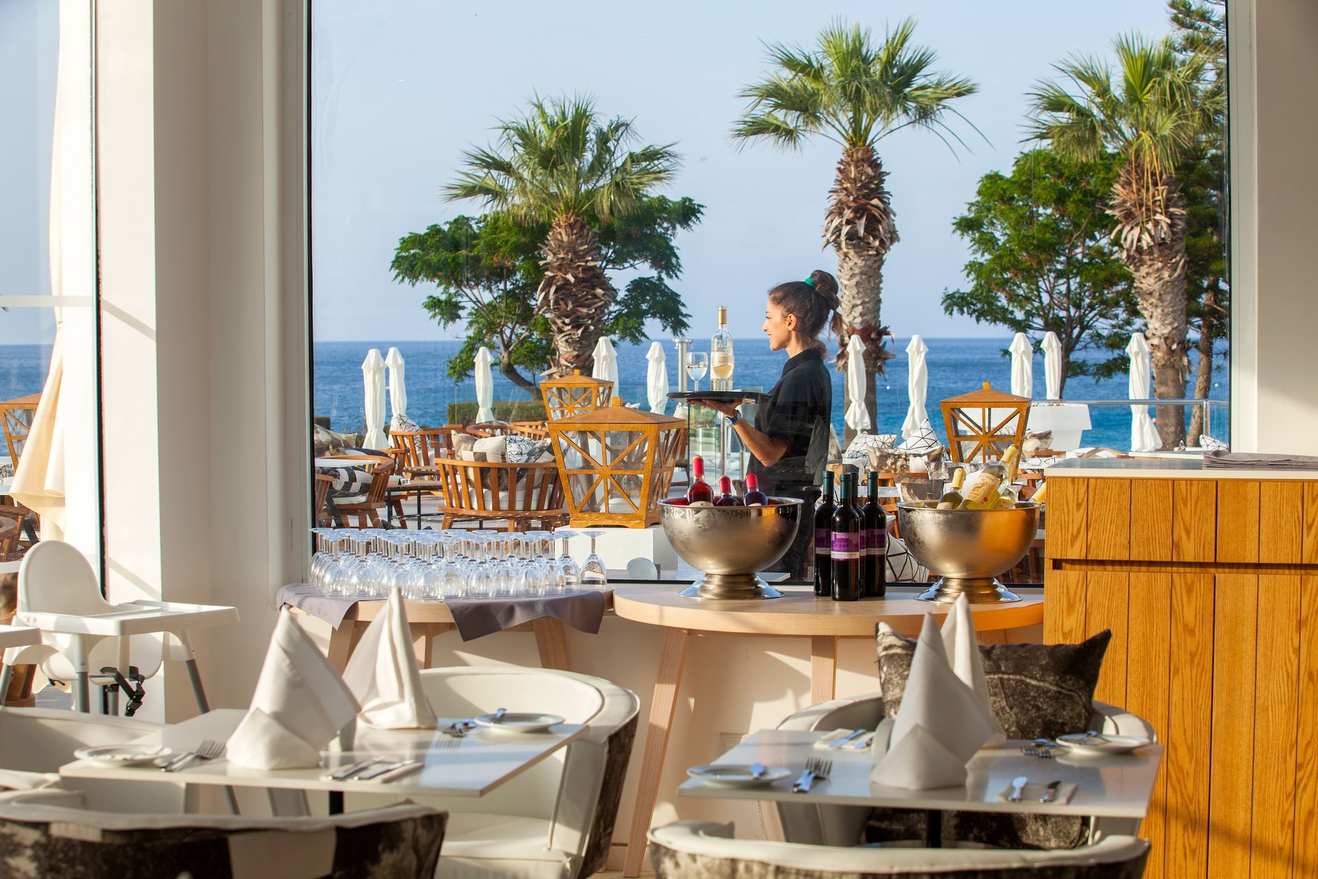 King Jason Protaras restaurant with server holding tray, ocean view, palm trees.