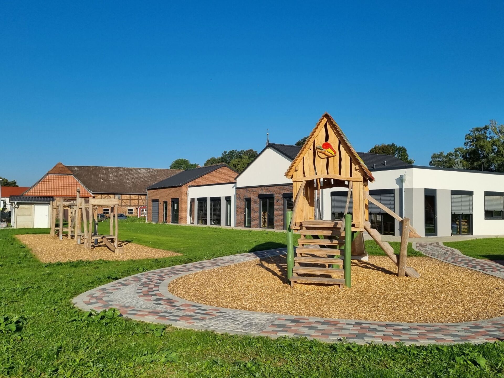 Ein Holzspielplatz mit einem Haus im Hintergrund.