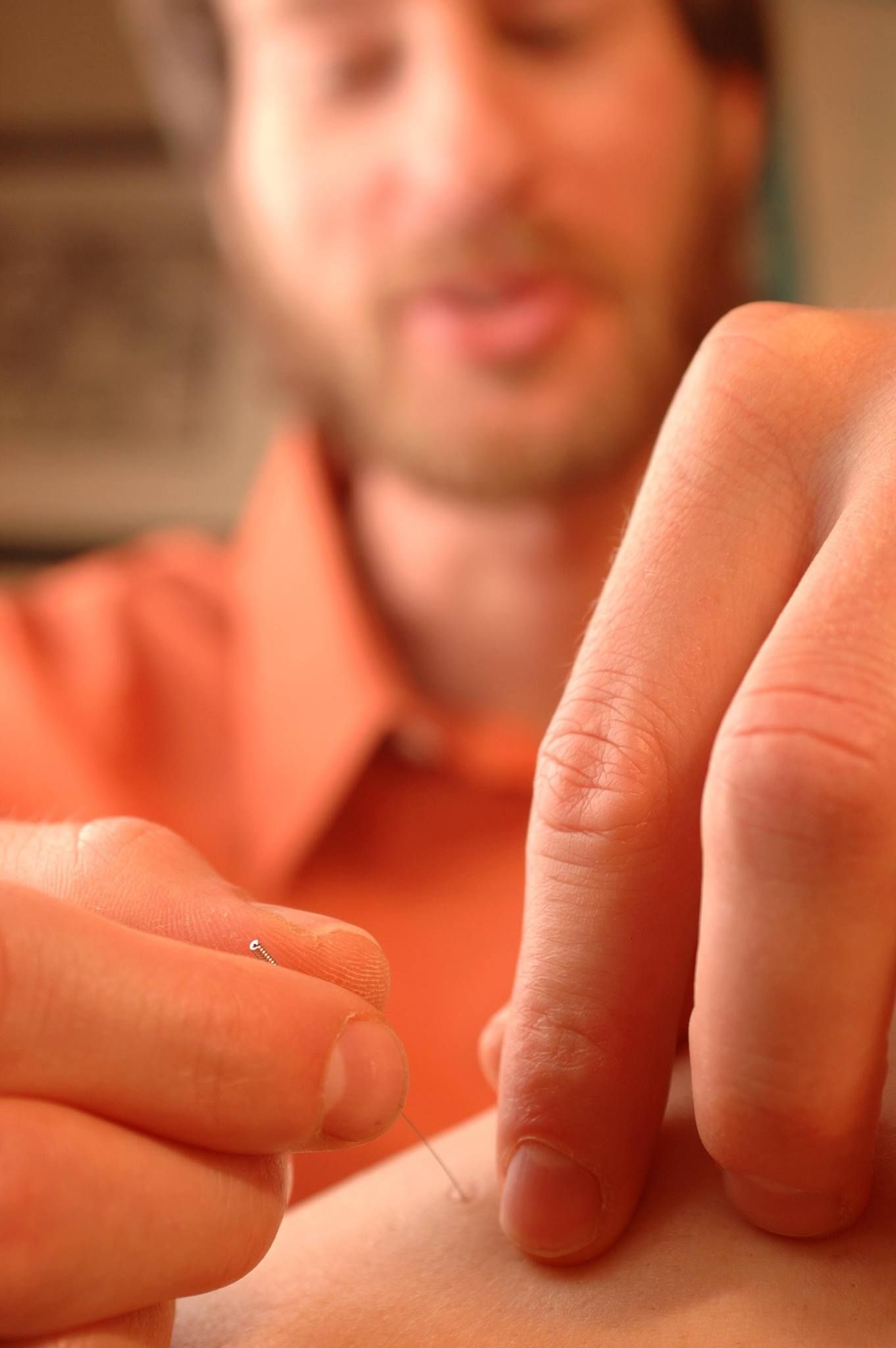 Close-up of a person placing a finger on another’s skin, with a blurred face in the background.