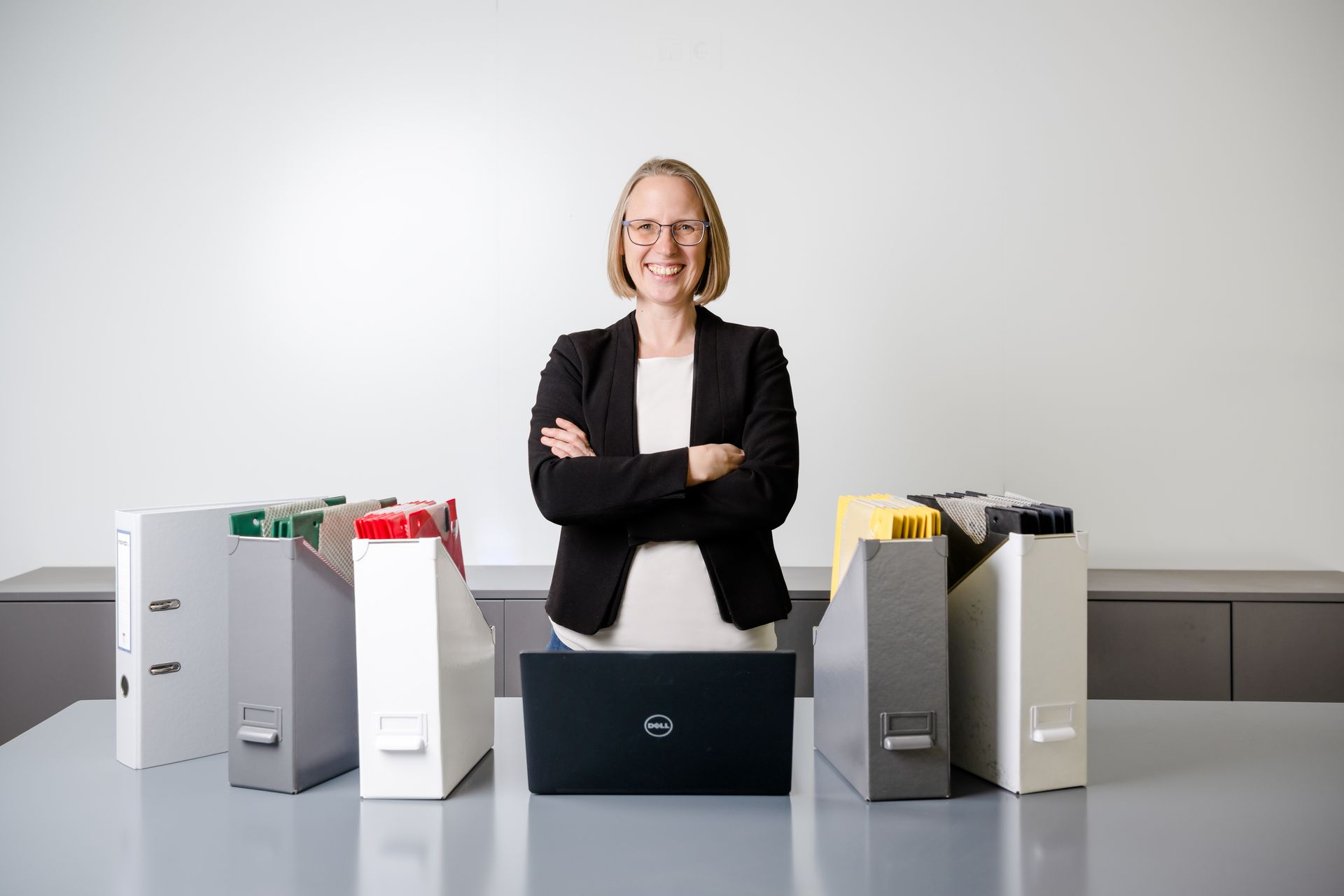 Birgit Holzbecher mit schwarzem Blazer vor einem Schreibtisch