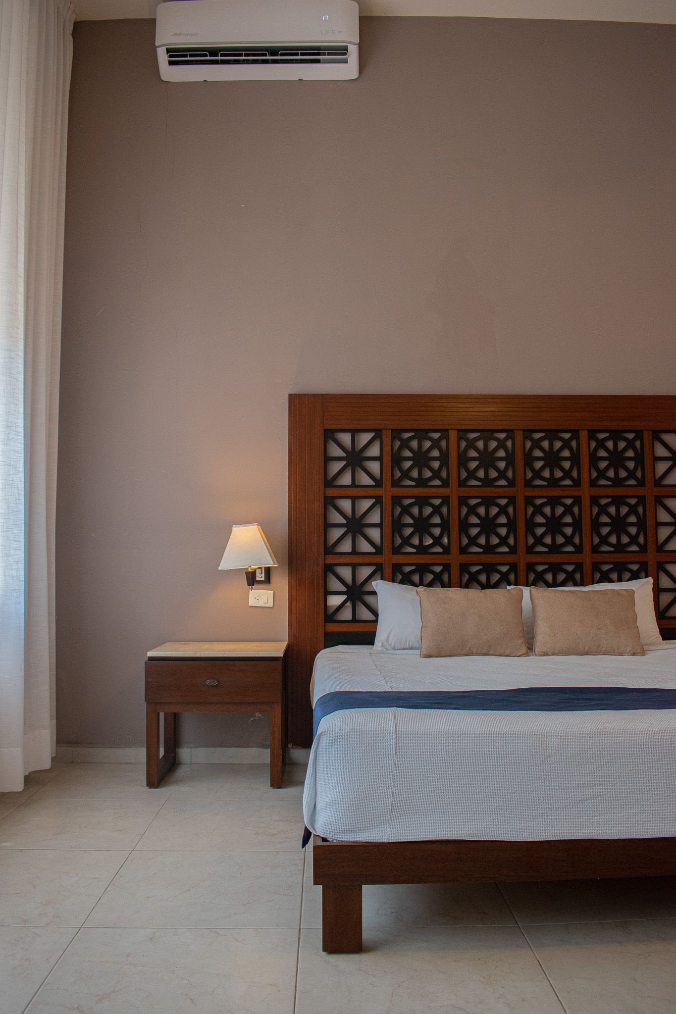 Un dormitorio con cama, mesita de noche y aire acondicionado.