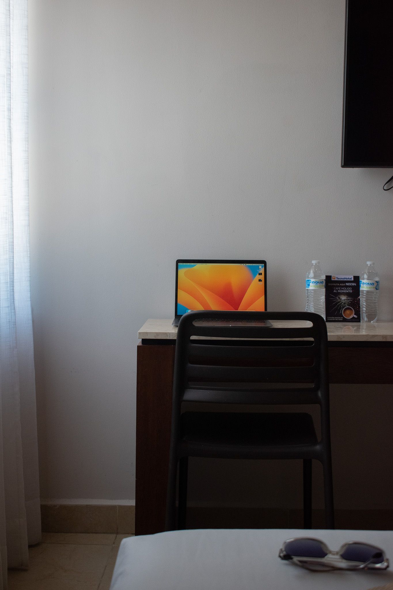 Una computadora portátil está sobre un escritorio al lado de una silla.