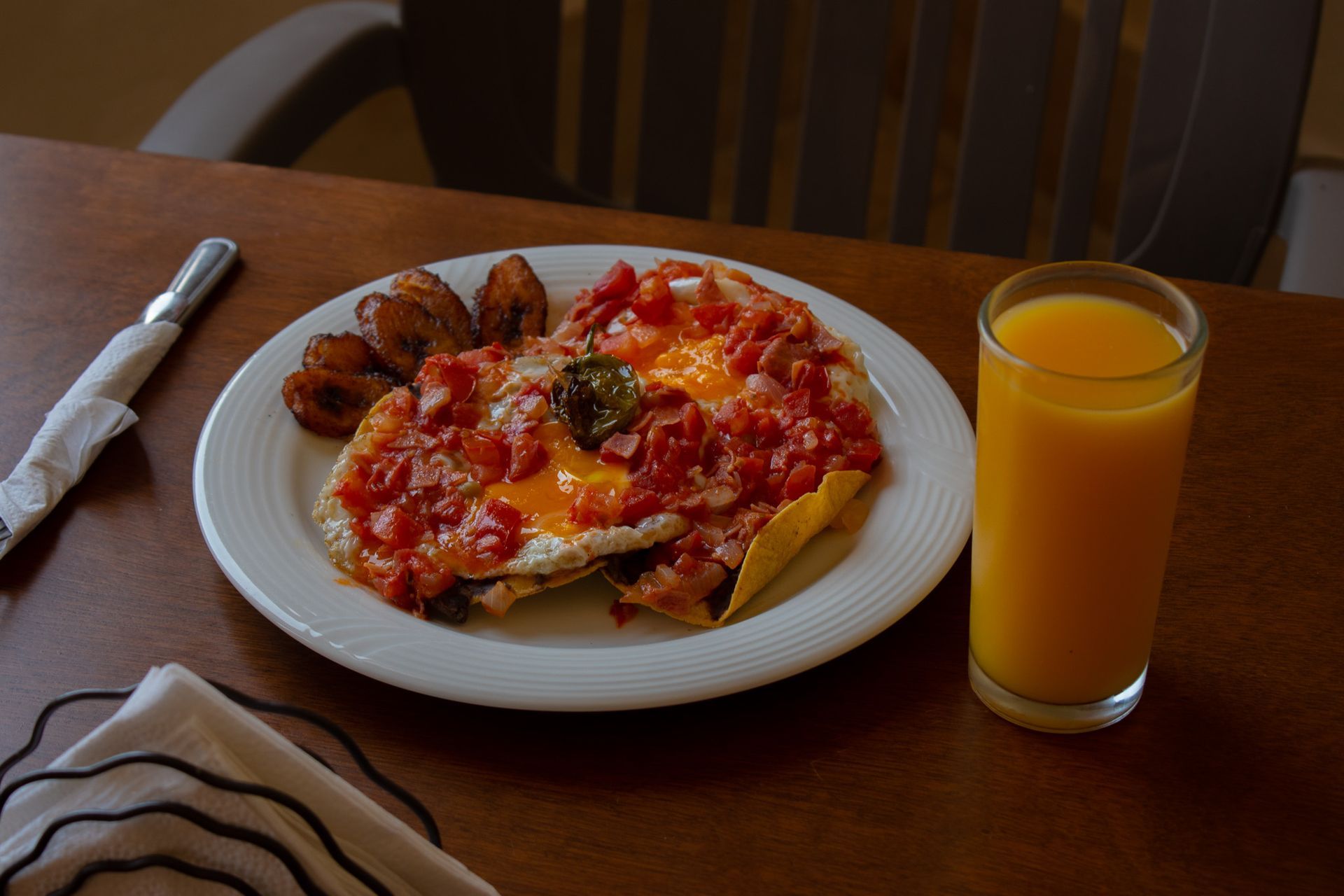 Un plato de comida y un vaso de jugo de naranja en una mesa.