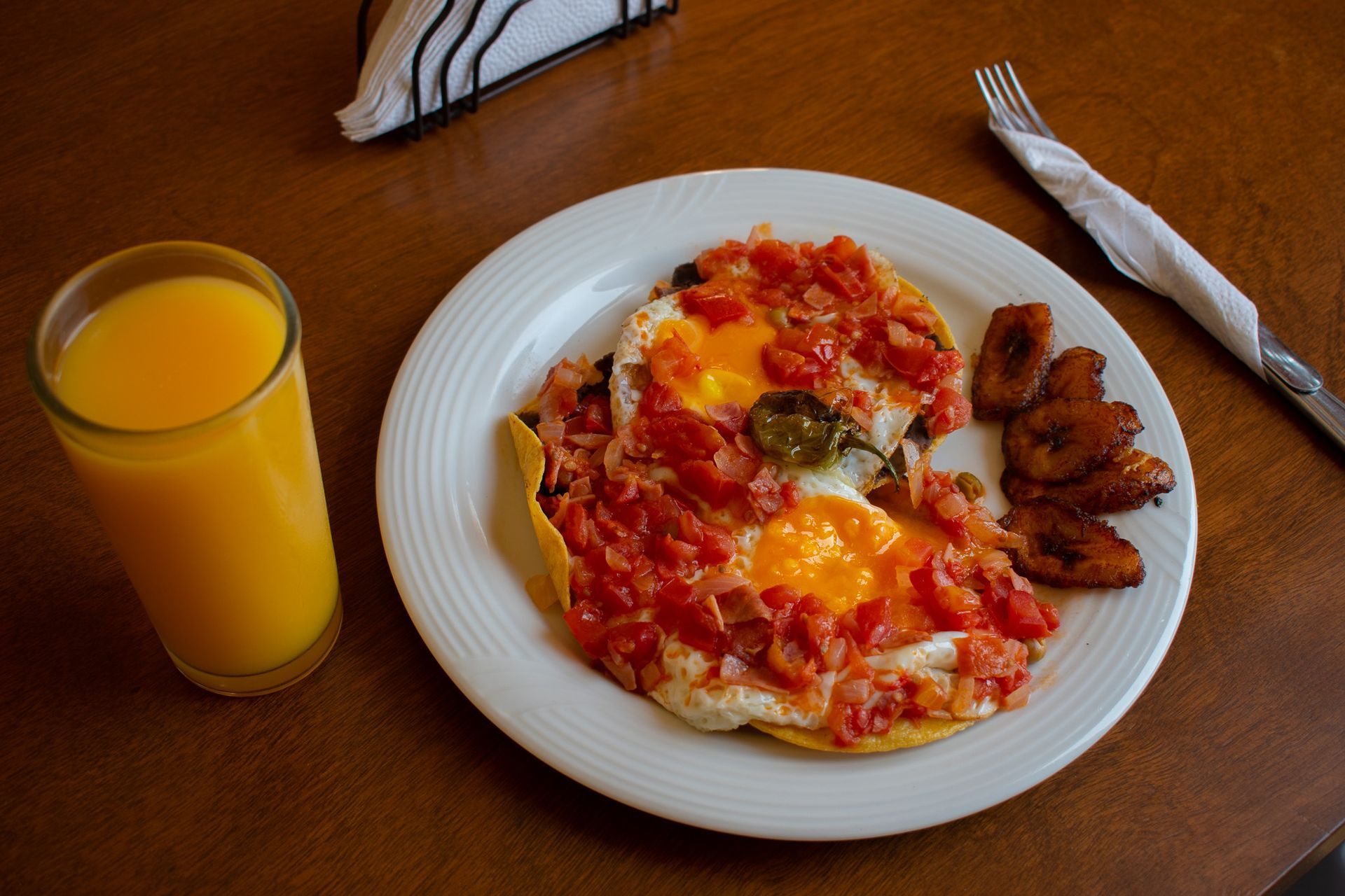 Un plato de comida y un vaso de jugo de naranja en una mesa.