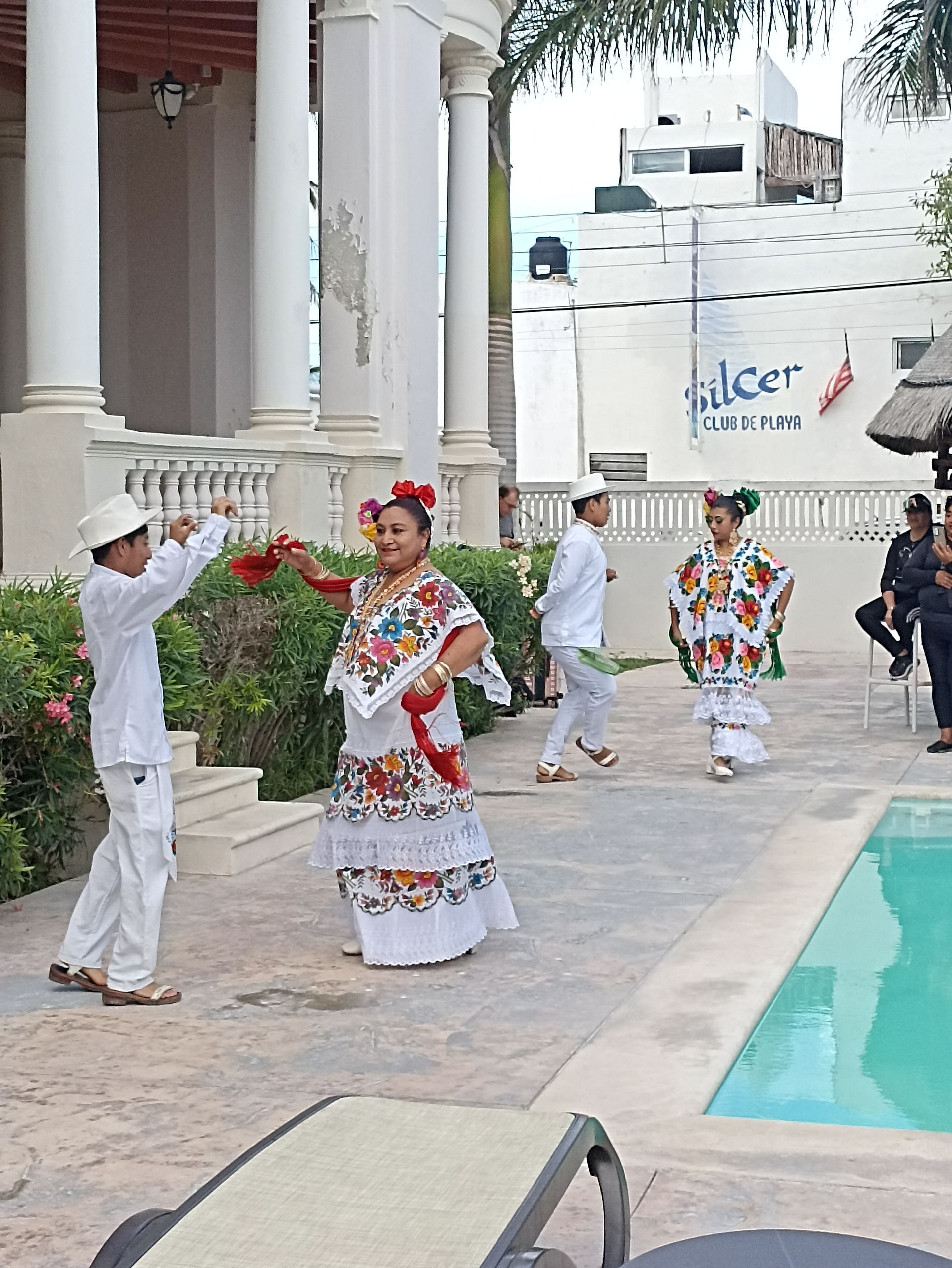 Un grupo de personas está bailando frente a una piscina.
