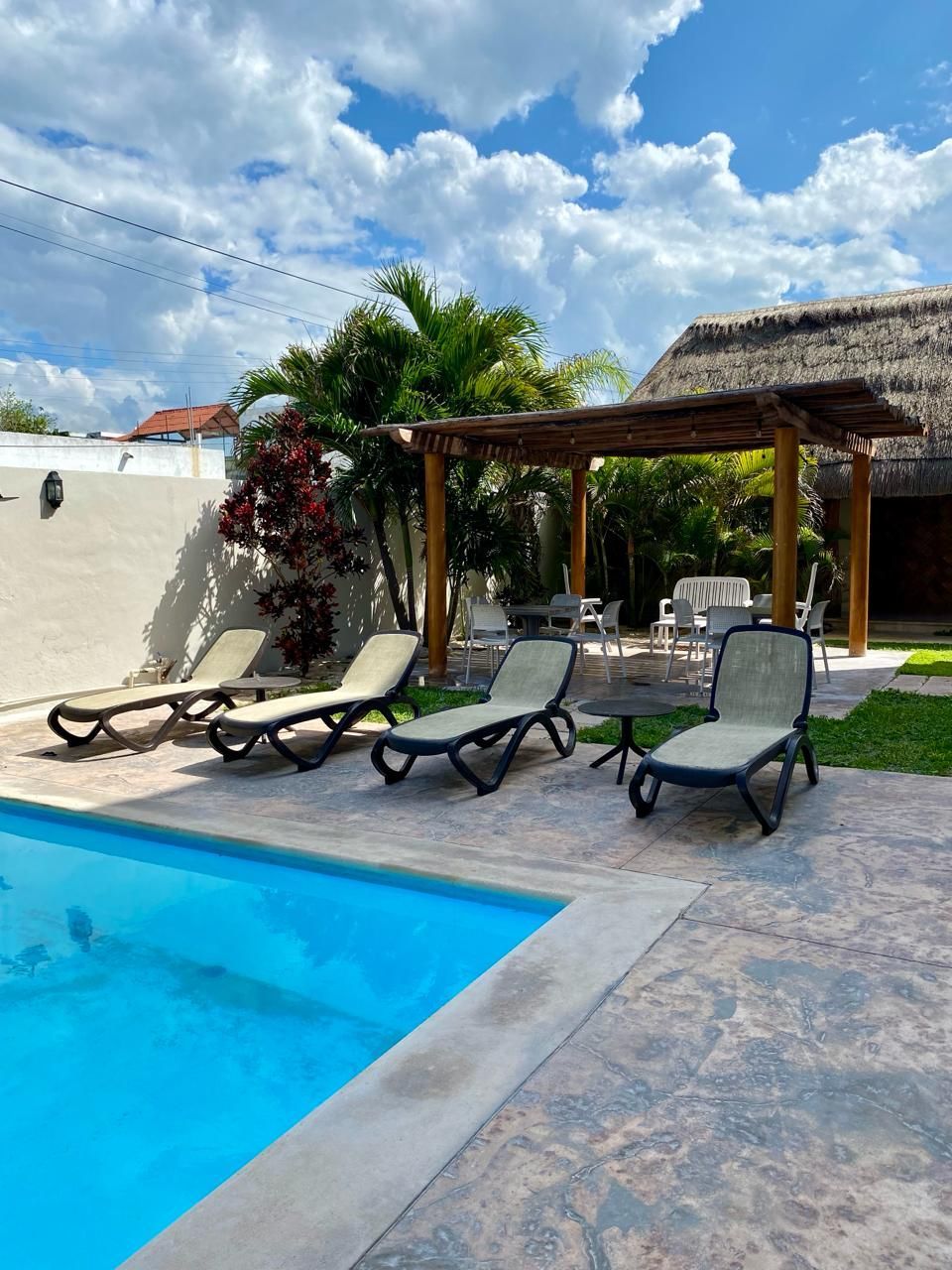 Una piscina con sillas y techo de paja.