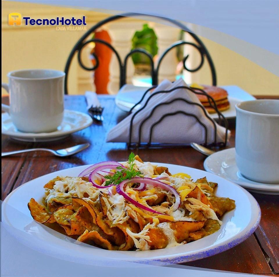 Un plato de comida sobre una mesa con el logo de un tecnohotel al fondo.