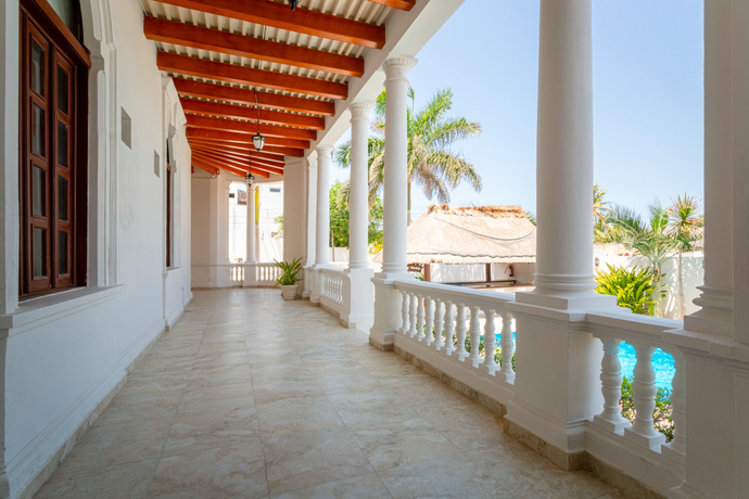 Un largo pasillo blanco con columnas y un techo de madera que conduce a un balcón.