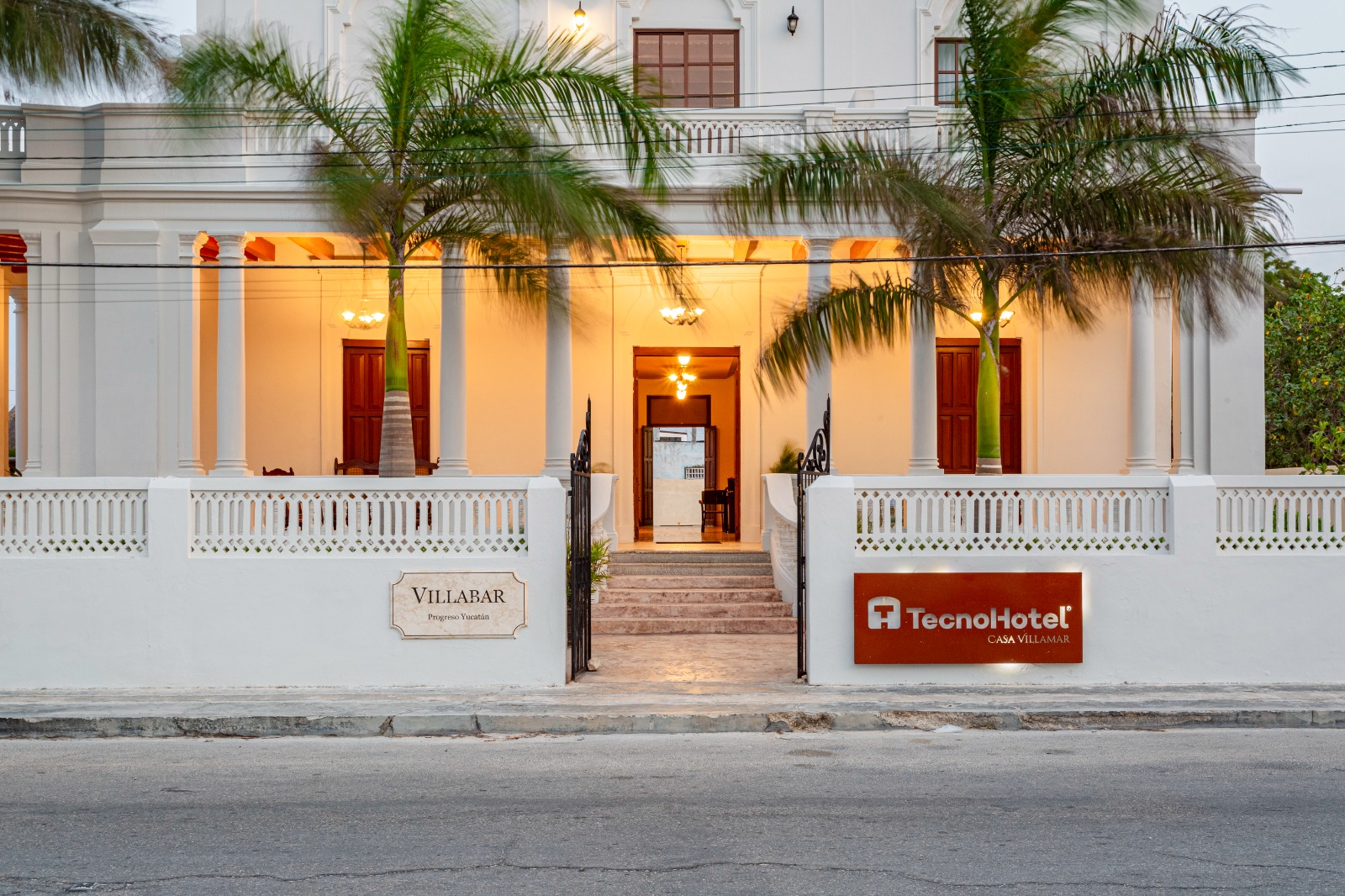 Un gran hotel blanco con palmeras delante.