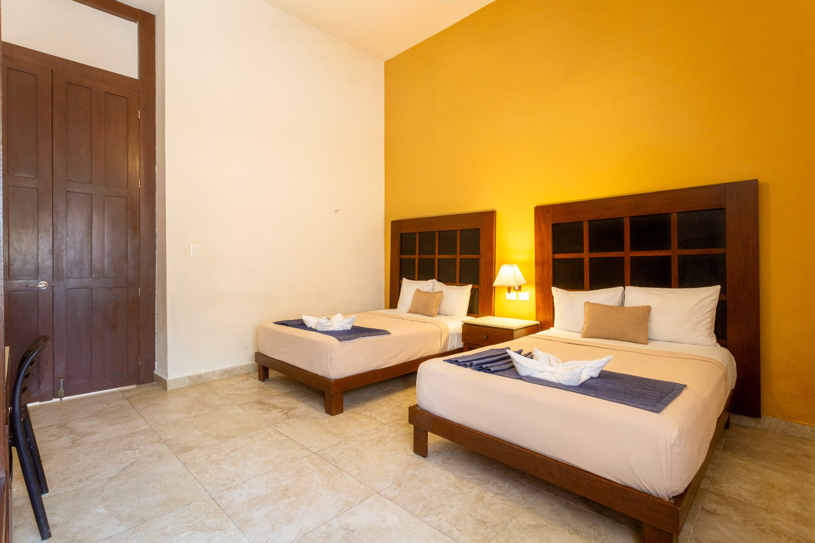 Una habitación de hotel con dos camas y una pared amarilla.