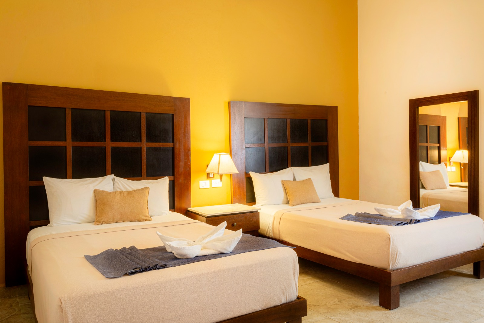 Una habitación de hotel con dos camas y un espejo.