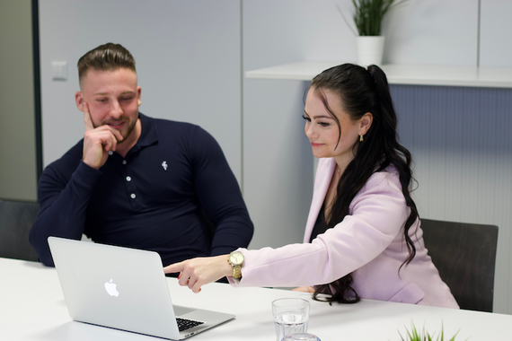 Ein Mann und eine Frau sitzen an einem Tisch und schauen auf einen Laptop.