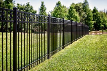 A Black Metal Fence Surrounds A Lush Green Field — Rabbo's Fencing Services In Pinelands, NT