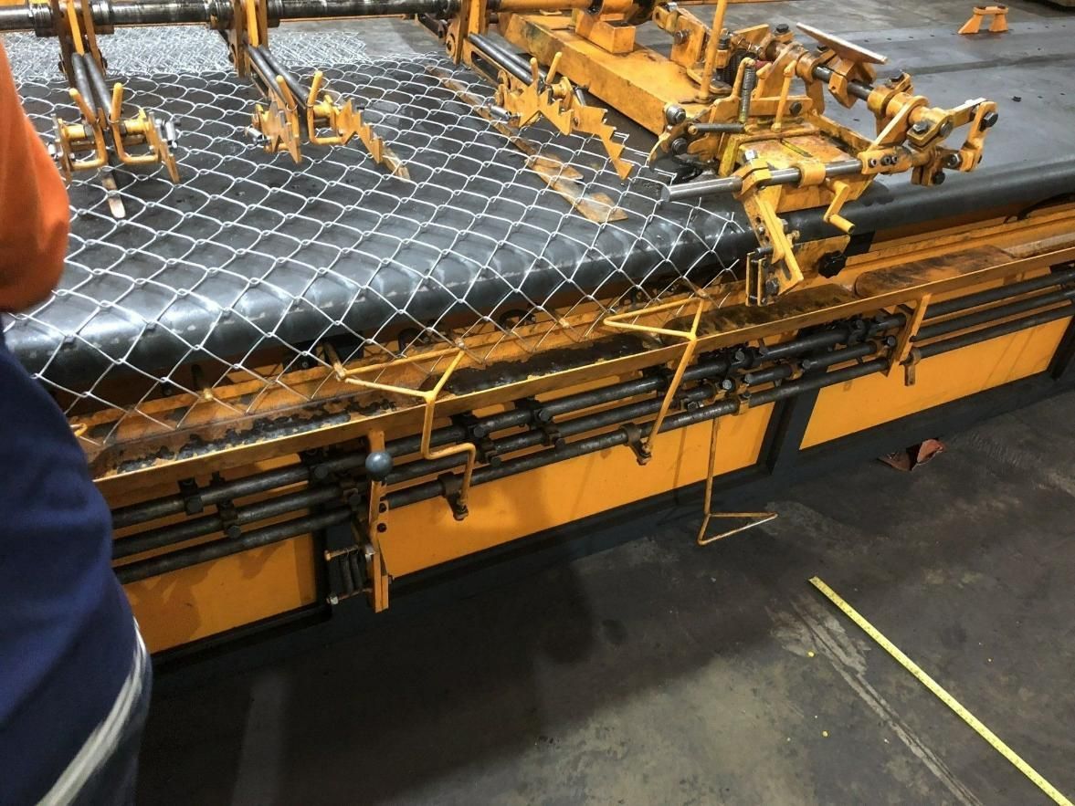 A Person Is Standing Next To A Large Yellow And Black Machine — Rabbo's Fencing Services In Pinelands, NT