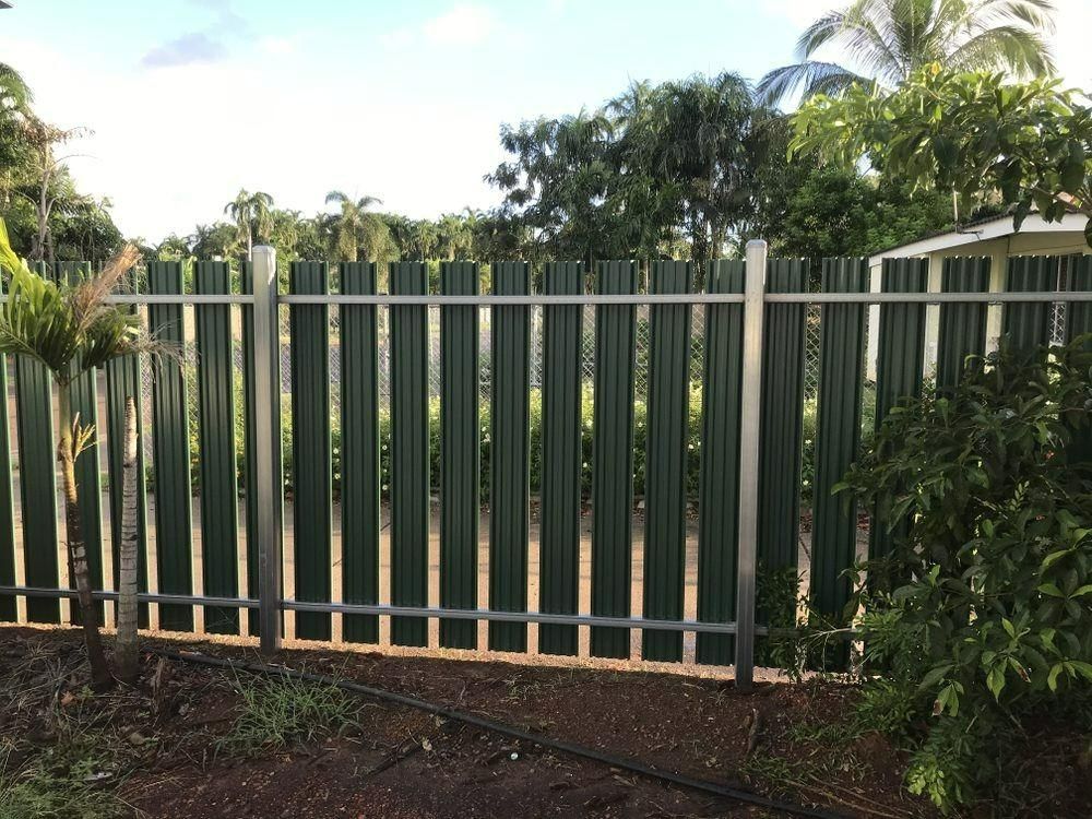 A Green Metal Fence With A Few Trees In The Background — Rabbo's Fencing Services In Pinelands, NT