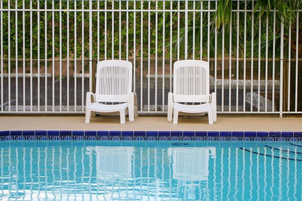 A White Fence Surrounds A Driveway Leading To A House — Rabbo's Fencing Services In Pinelands, NT