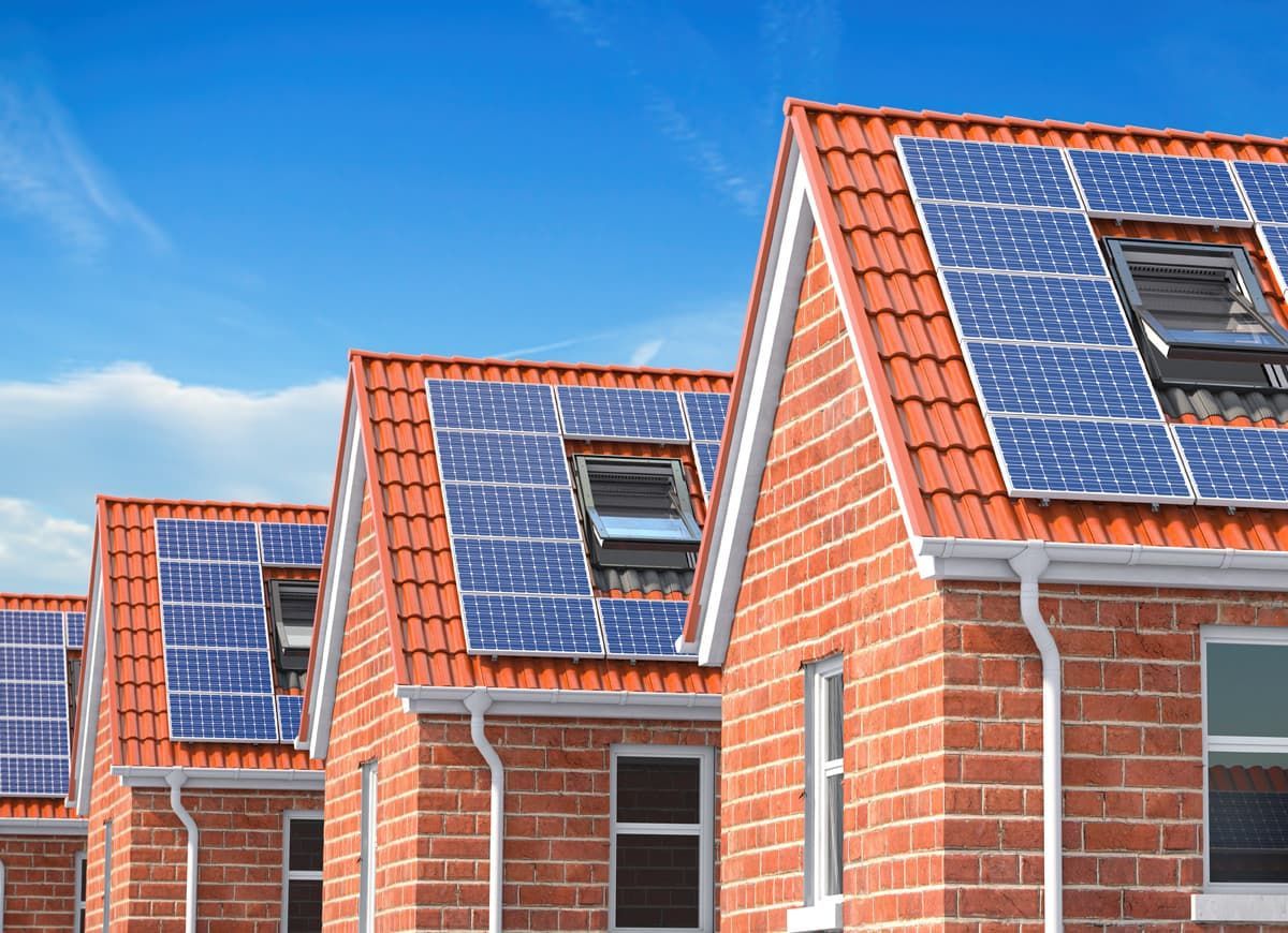 A row of brick houses with solar panels on the roofs.