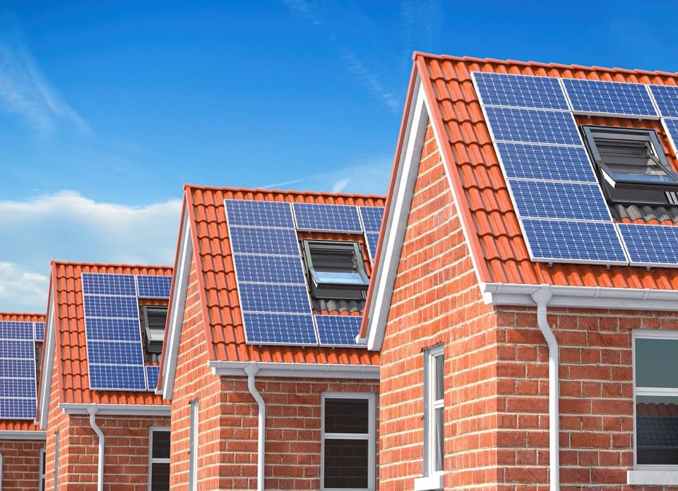 A row of brick houses with solar panels on the roofs.