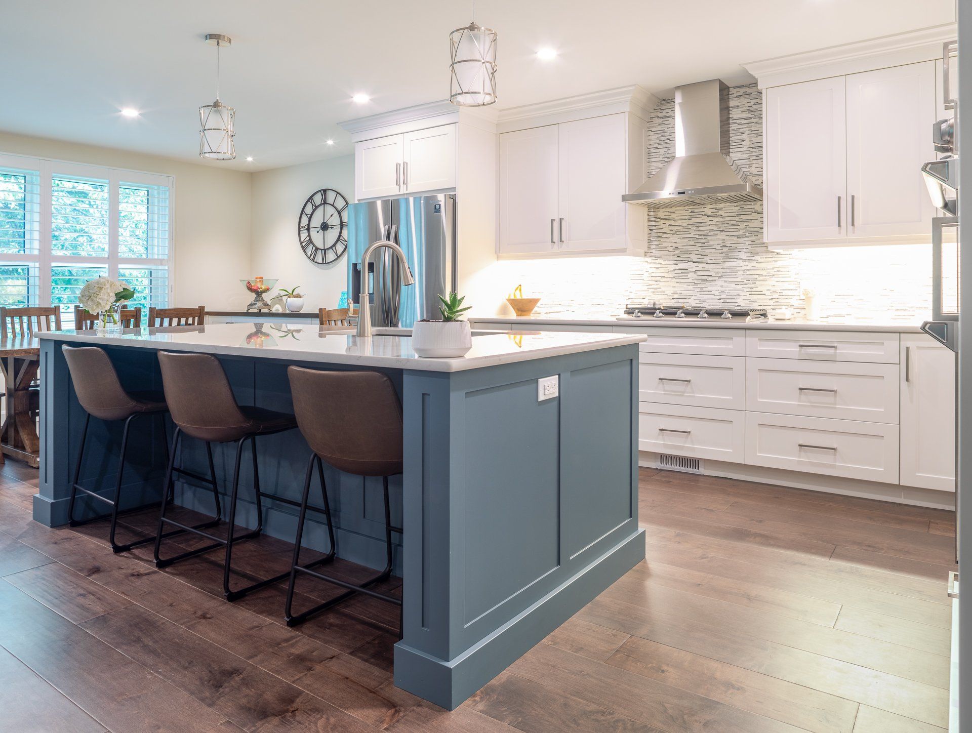 a kitchen with white cabinets and a blue island with stools .