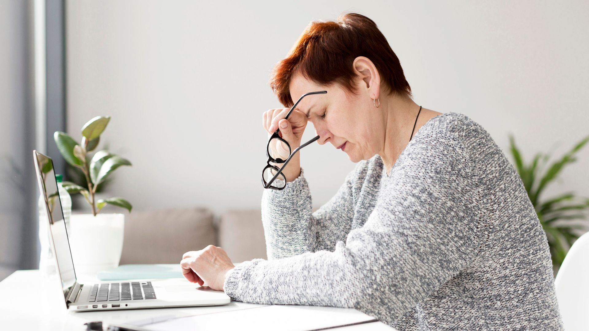 Lady at her desk expressing symptoms of stress and anxiety