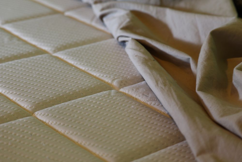 A Beige Mattress with A Light Grey Sheet Being Pulled Up — Water Works Waterbeds in Gold Coast, QLD