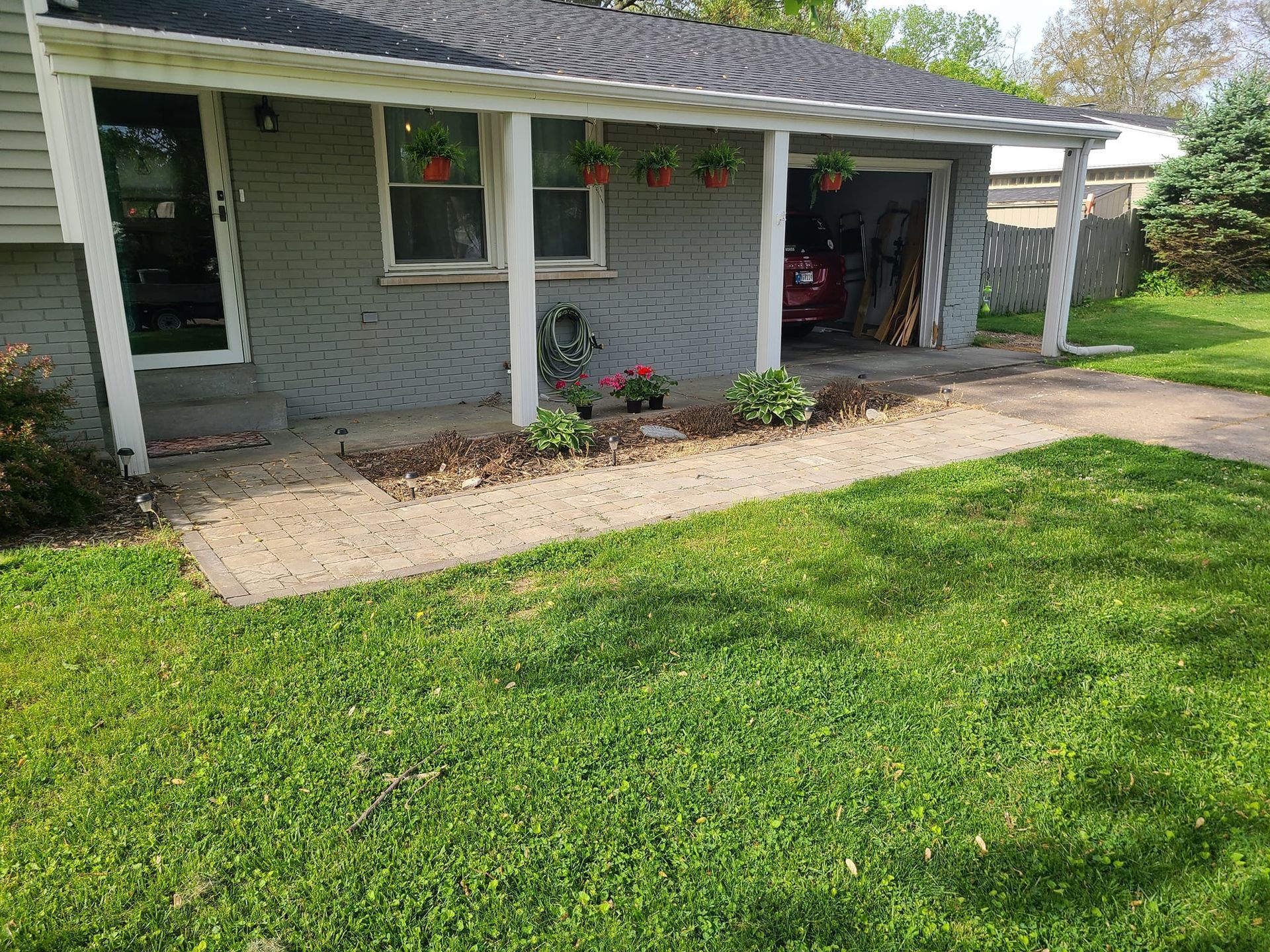 Gray house with small garden bed and concrete walkway leading to the front door and attached garage.