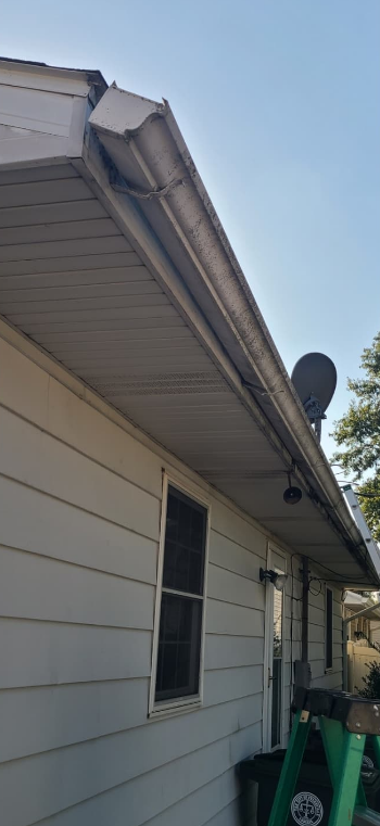 A house's siding and gutter with a visible satellite dish and a window.