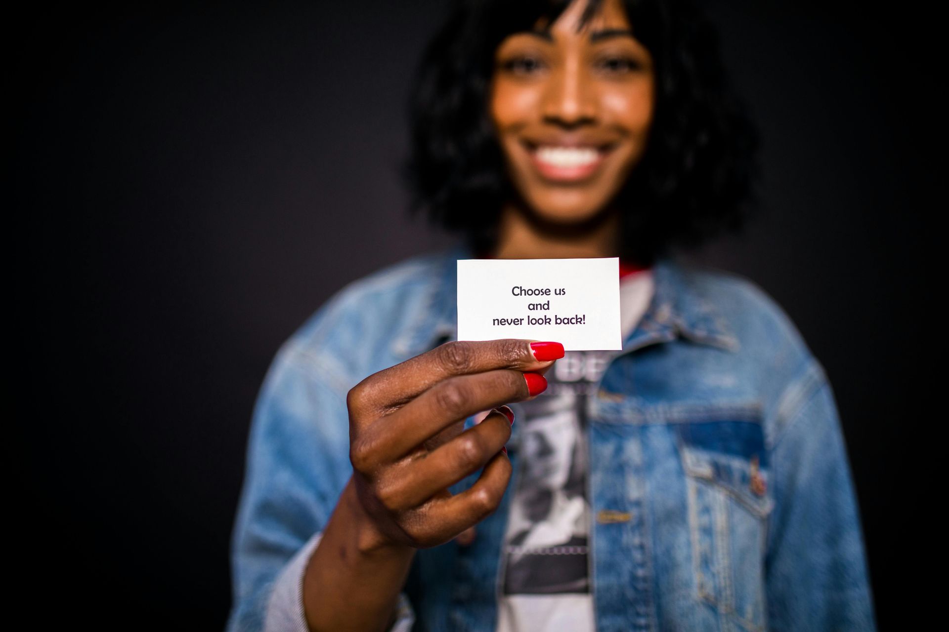 Woman in denim jacket holds a card reading