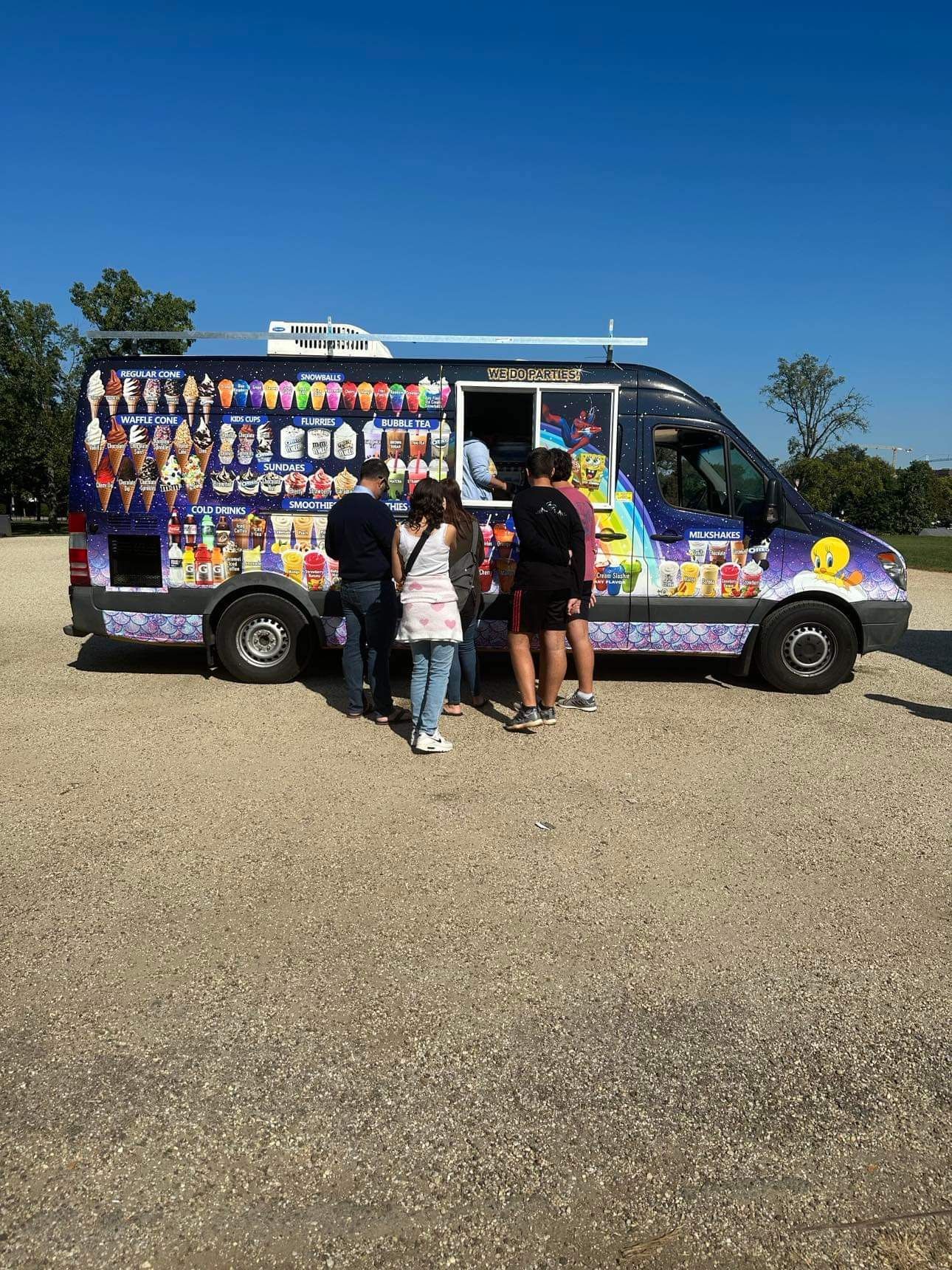 A group of people are standing in front of an ice cream truck.