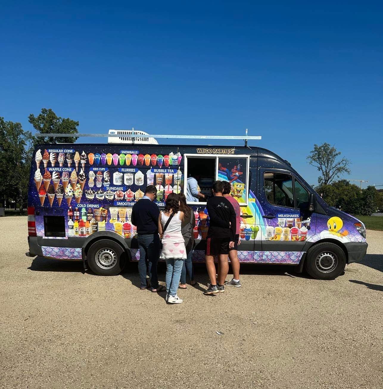A group of people standing in front of an ice cream truck that says it 's cool