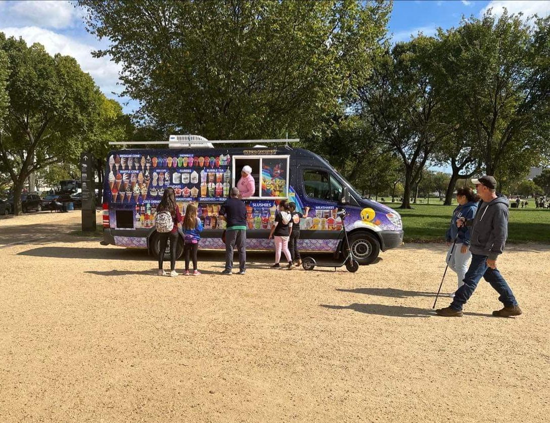 A group of people are standing in front of an ice cream truck.