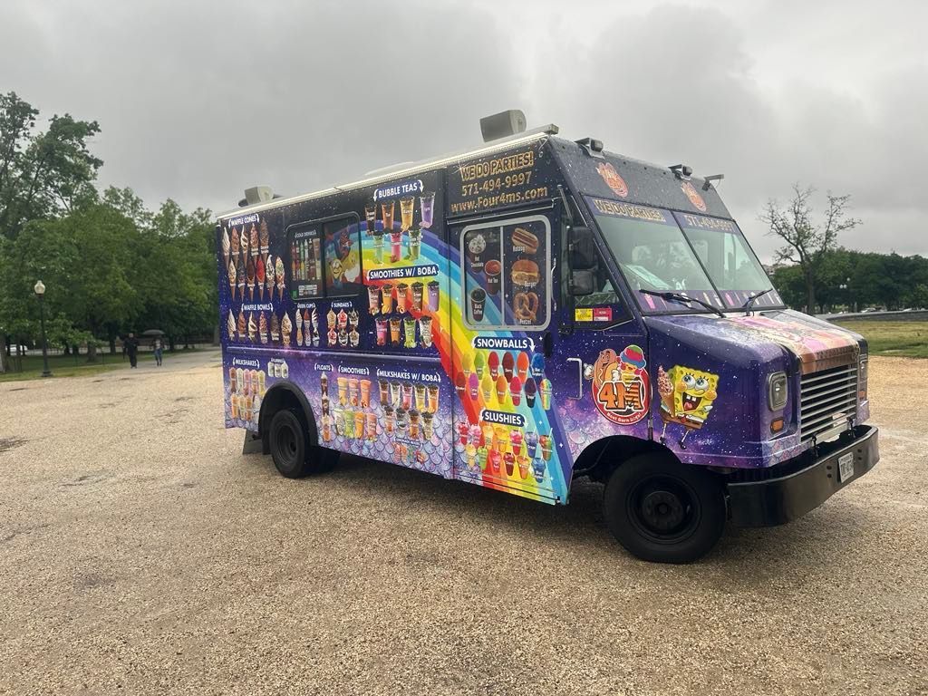 A colorful food truck is parked in a gravel lot.