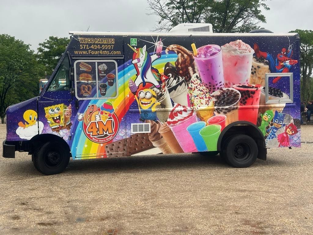 A colorful ice cream truck is parked in a gravel lot.