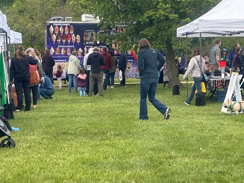 A group of people are standing in a grassy field in front of an ice cream truck.