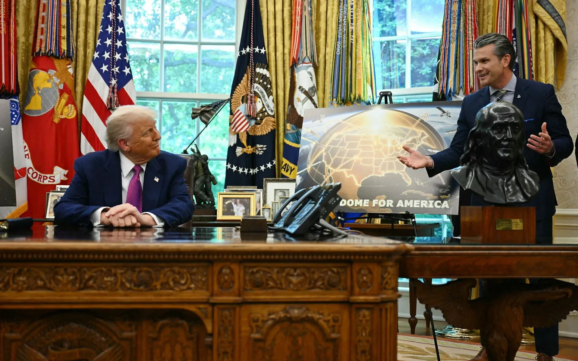 Two men are sitting at a desk in front of a sign that says joint force africa