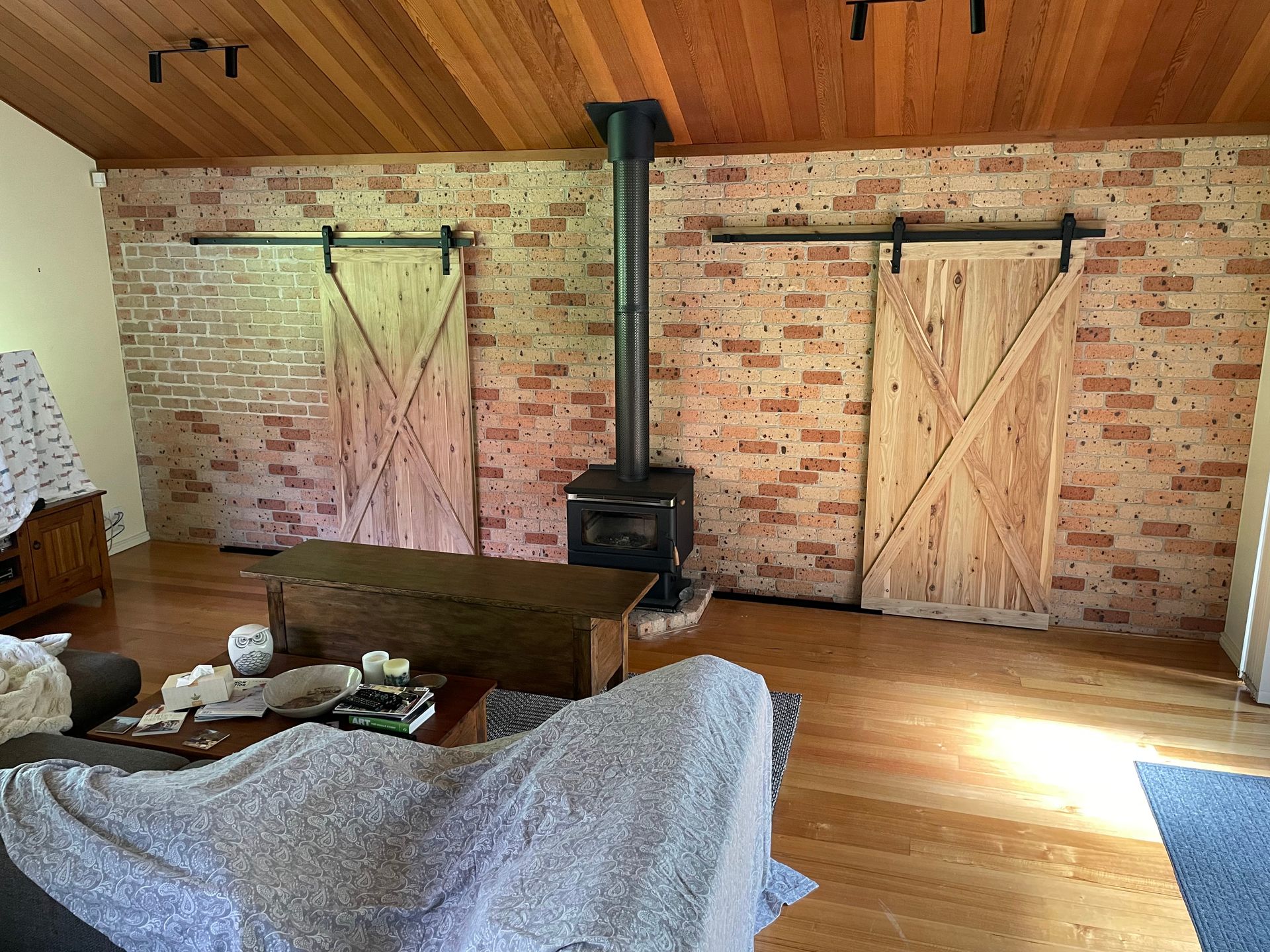 A living room with sliding barn doors and a wood stove.