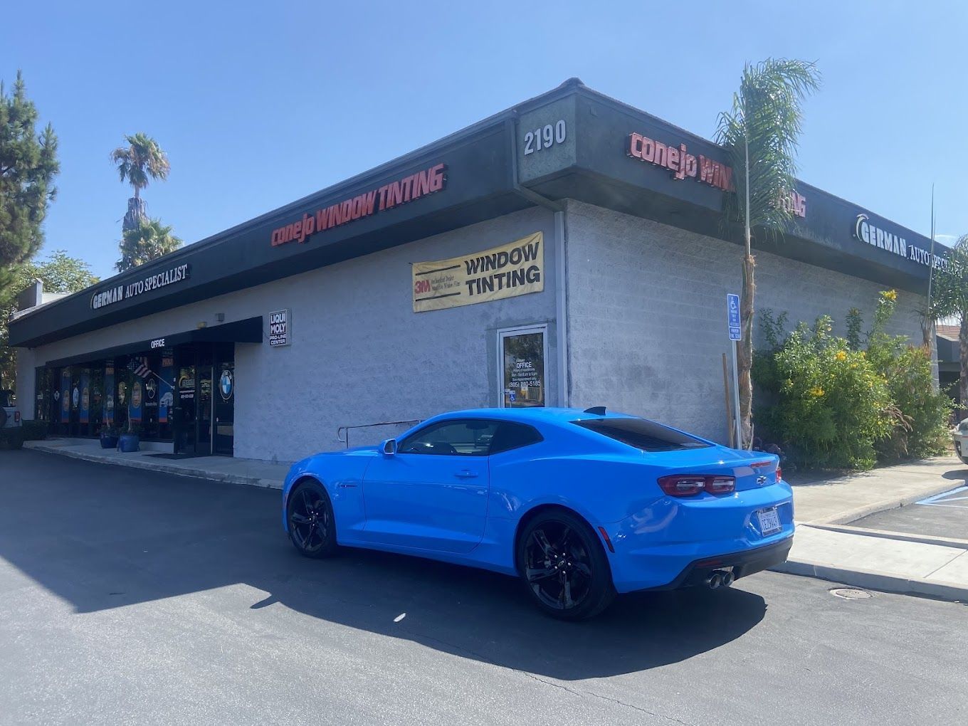 A blue car is parked in front of a building.