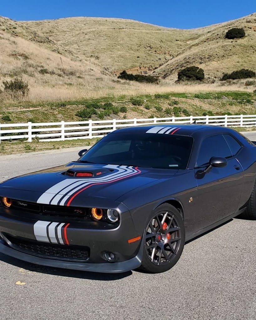 A black dodge challenger is parked on the side of the road