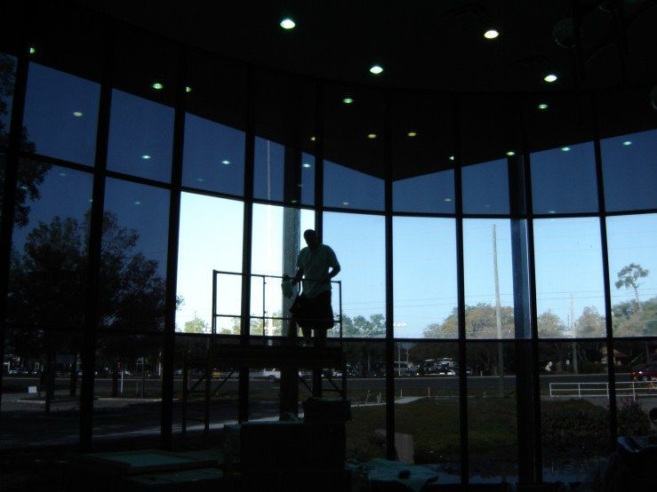A silhouette of a man standing in front of a large window